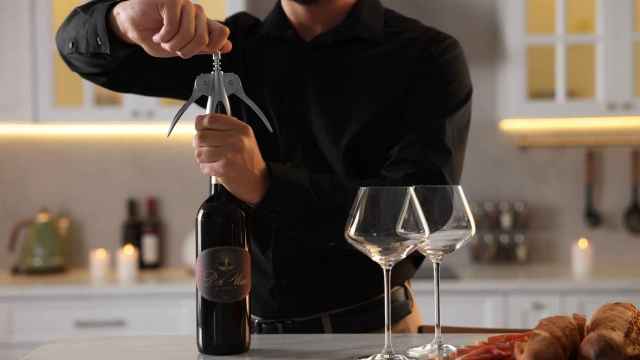 Un hombre abriendo una botella de vino