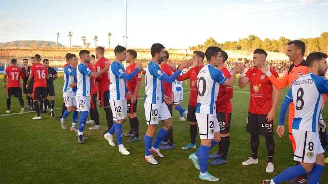 Los jugadores del hércules saludan a los de La Nucía en los prolegómenos de un partido.