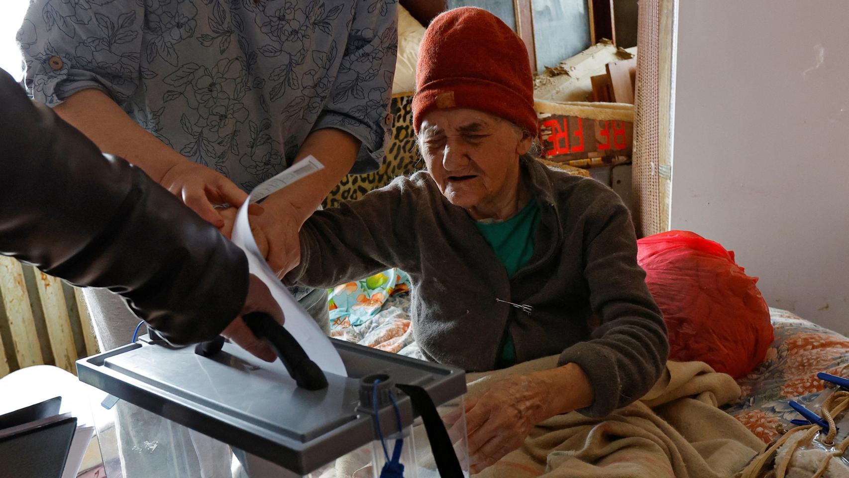 Una señora deposita su voto en una urna móvil que los agentes rusos han llevado a su casa, el lunes en Dónetsk.