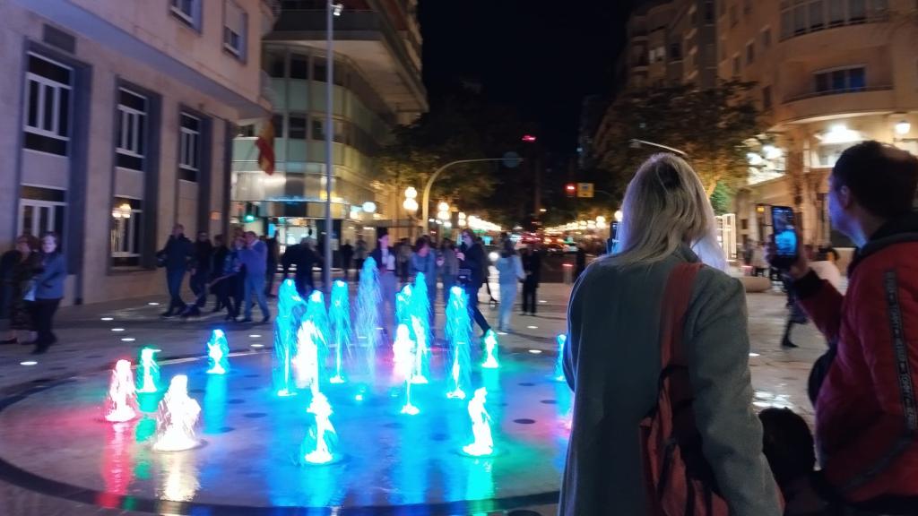 Los paseantes este viernes fotografiando las luces de la fuente.