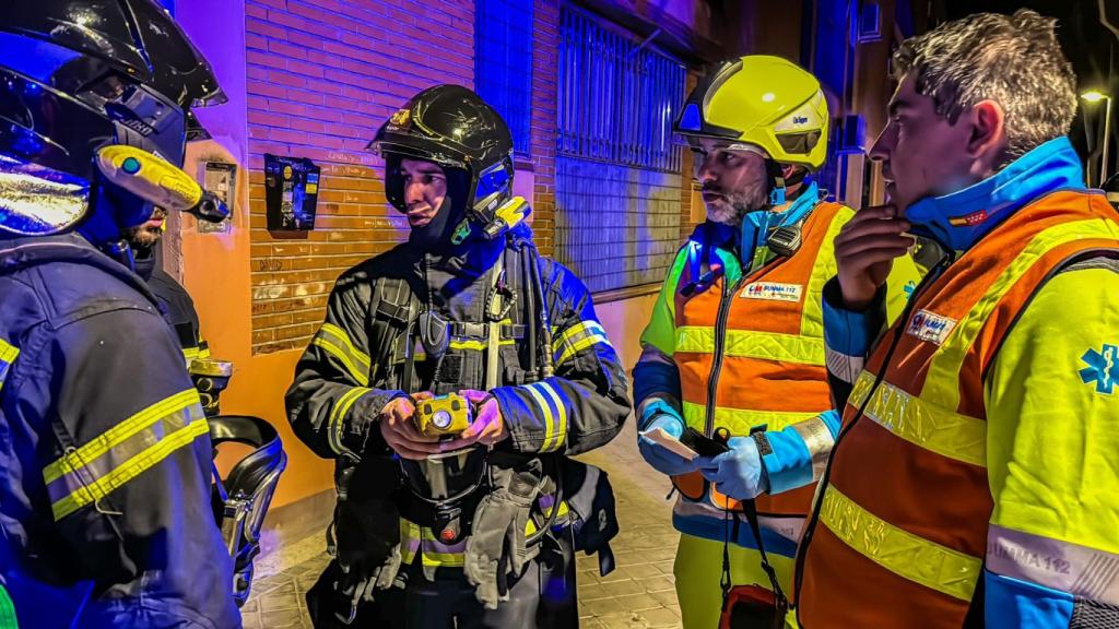 Bomberos y sanitarios en el portal del edificio afectado.