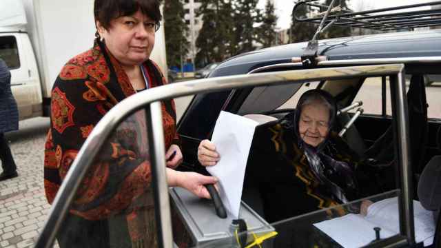 Una mujer deposita su voto en una urna electoral móvil durante las elecciones presidenciales en Donetsk, parte de Ucrania controlada por Rusia.