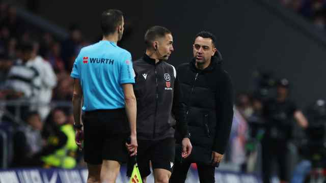 Xavi protesta una acción al linier y al cuatro árbitro durante el Atlético de Madrid - Barcelona.