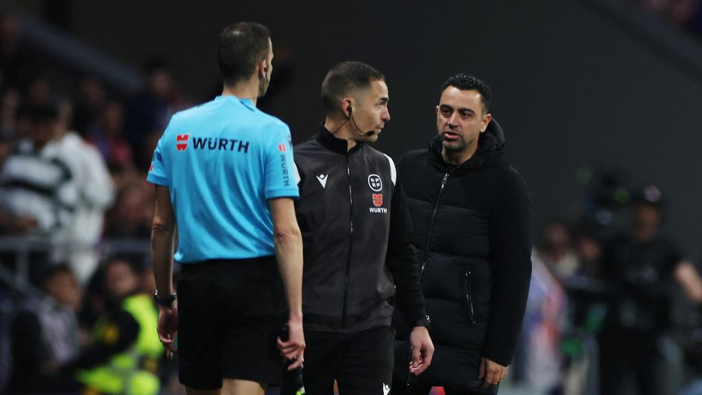 Xavi protesta una acción al linier y al cuatro árbitro durante el Atlético de Madrid - Barcelona.