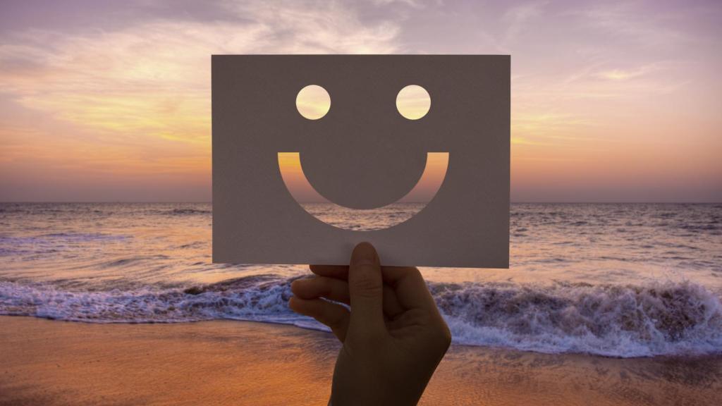 Papel con cara feliz en una playa durante el atardecer.