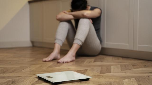 Mujer llorando junto a una báscula.