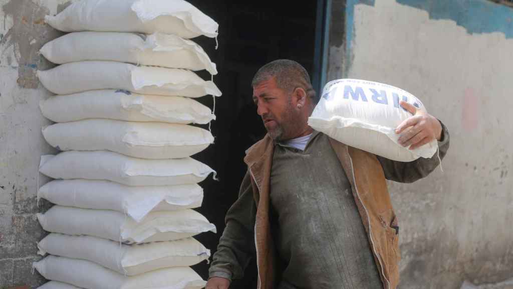 Un palestino carga un saco de harina proporcionado por la UNRWA.