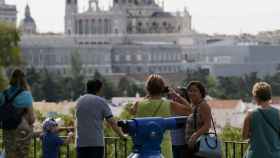 Varias personas observan las vistas del Palacio Real y la catedral de la Almudena desde los jardines del templo de Debod, en Madrid.