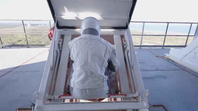 Una astronauta descendiendo por el tobogán de emergencia