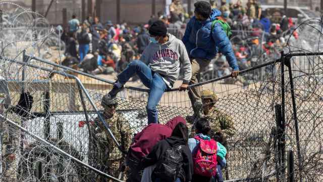 Dos jóvenes saltan una valla, este jueves en Ciudad Juárez.