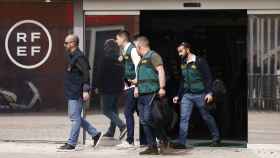 Un agente de la Europol y varios agentes de la Unidad Central Operativa (UCO) de la Guardia Civil salen de la Real Federación Española de Fútbol