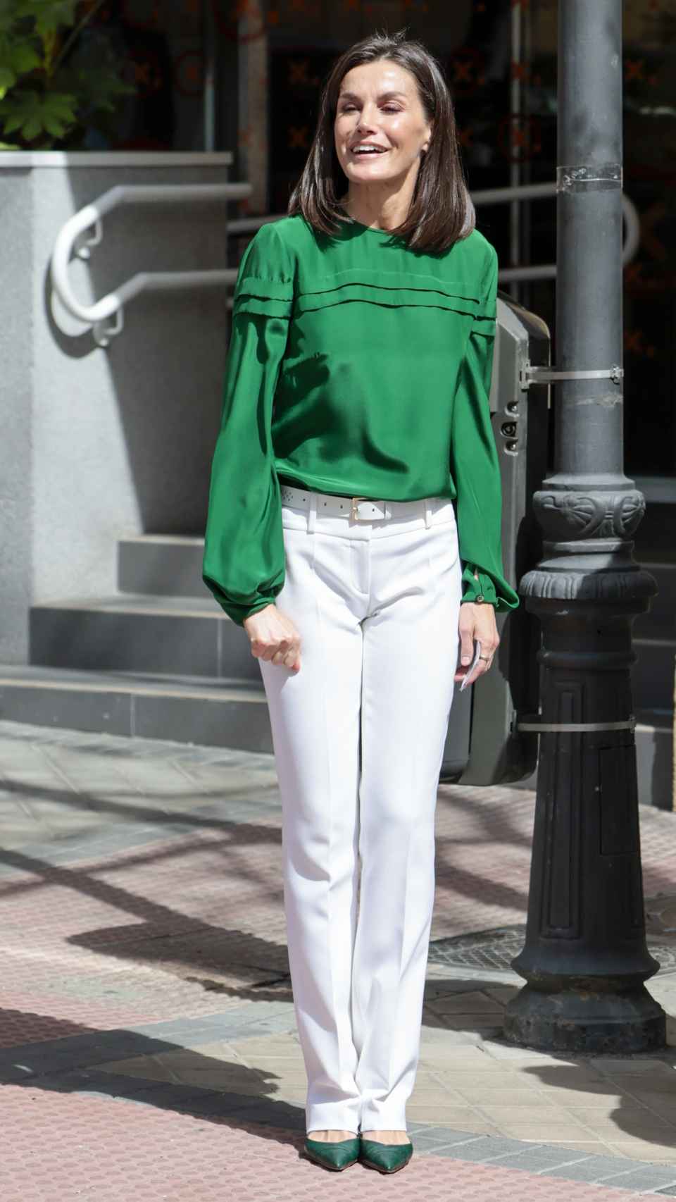 Letizia con el look de blusa verde y zapatos a juego con pantalones blancos.