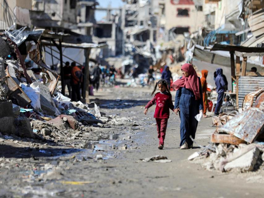 Una madre pasea junto a su hija entre ruinas en una zona atacada por Israel en Gaza.