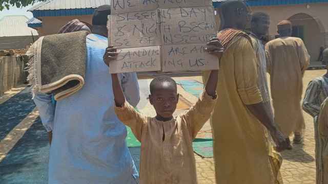 Un niño sostiene un cartel para protestar contra el secuestro de cientos de alumnos por hombres armados en Kaduna, Nigeria.