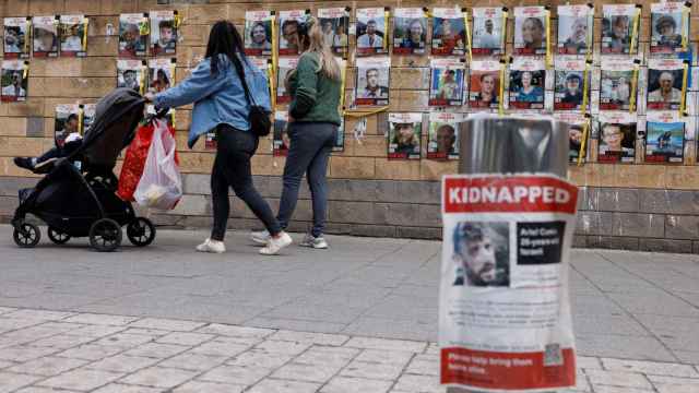 Personas caminan en Tel Aviv junto a carteles con imágenes de los secuestrados en el ataque del 7 de octubre.