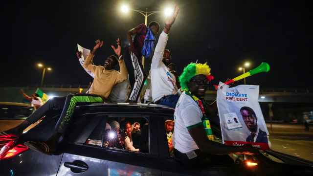Varios senegaleses celebran en un coche la victoria de Bassirou Diomaye Faye en las elecciones del domingo.