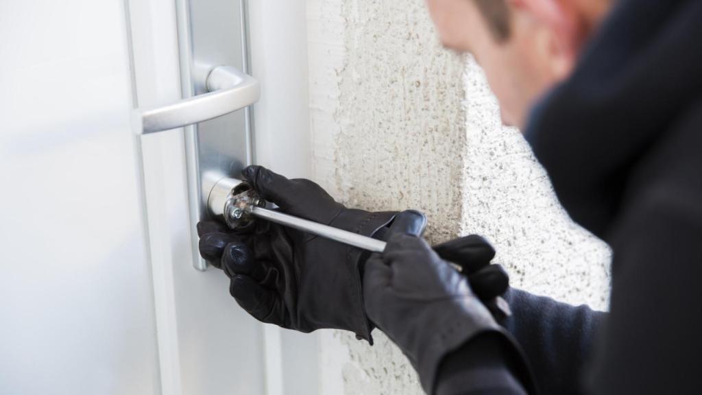 Imagen de un ladrón abriendo la cerradura de una casa