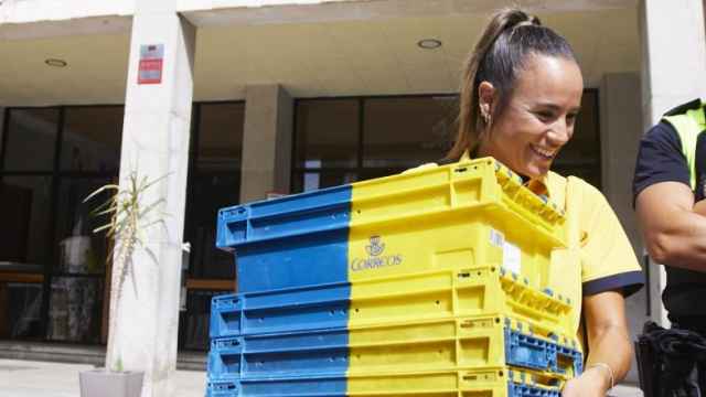 Una empleada de Correos recogiendo unas cajas en un colegio