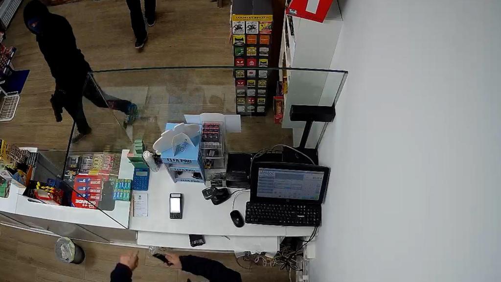 El pistolero oculta su rostro con el pasamontañas mientras encañona con un arma al dueño del estanco de Balsapintada, en la localidad murciana de Fuente Álamo.