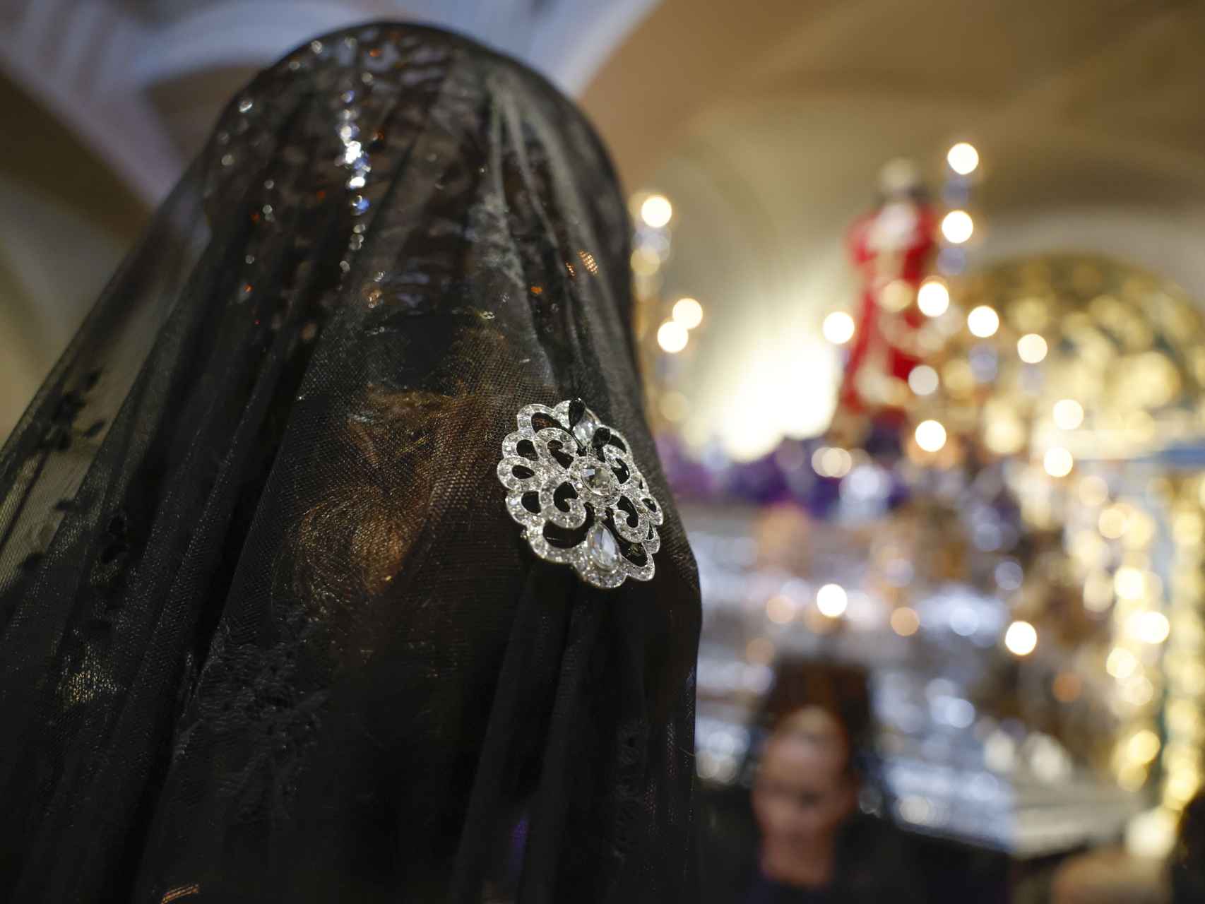 Mujeres con mantilla delante de la imagen de Jesús Nazareno El Pobre en la Iglesia de San Pedro 'El Viejo', durante la procesión de Jueves Santo en Madrid.