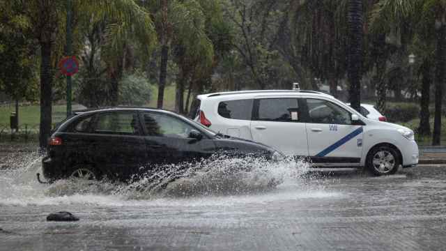Dos vehículos atraviesan una balsa de agua en Málaga capital.