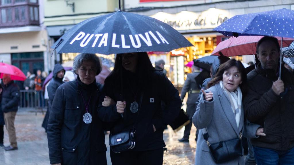 Dos mujeres se guarecen de la lluvia en un paraguas tras la suspensión de la procesión de la Virgen de la Soledad