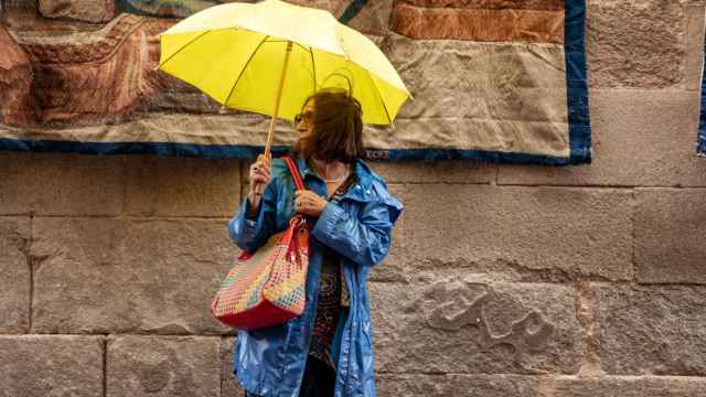Una mujer se protege de la lluvia en Toledo.