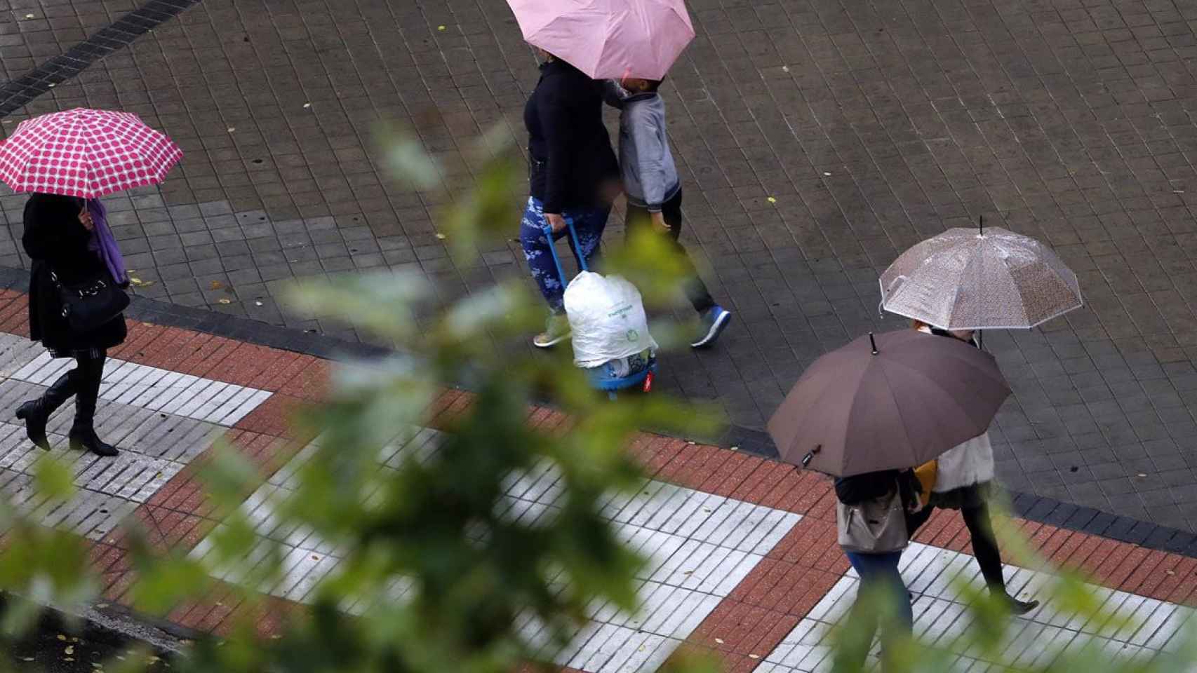 Imagen de archivo de varias personas protegiéndose de la lluvia.
