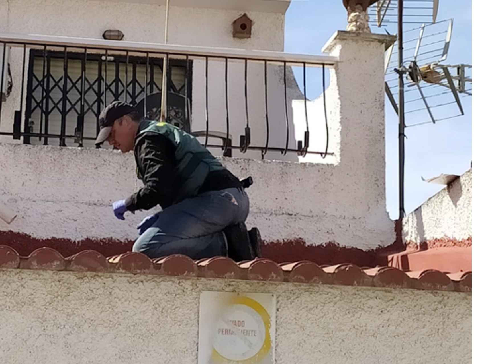 Un agente de la Policía Judicial inspeccionando el tejado de la casa de Julio por donde intentaron huir los ladrones.