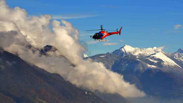 Un helicóptero sobrevolando montañas nevadas.