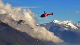 Un helicóptero sobrevolando montañas nevadas.