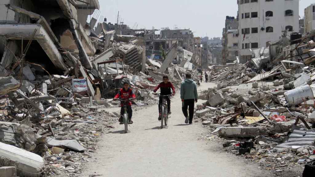 Niños palestinos montan en bici por las ruinas del norte de Gaza.