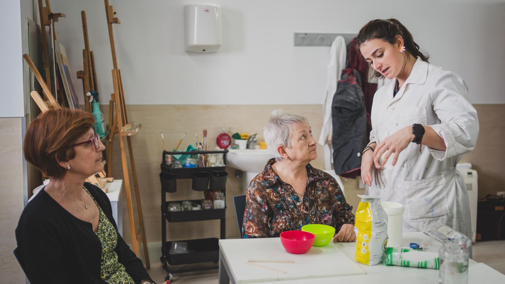 La profesora del taller de pintura, Ana Noci, explica a las abuelas grafiteras los pasos para hacer el molde de una mano para preparar su obra 'Dejando Huella'.