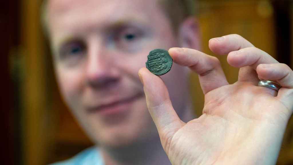 Rory Naismith sosteniendo una moneda de plata bizantina