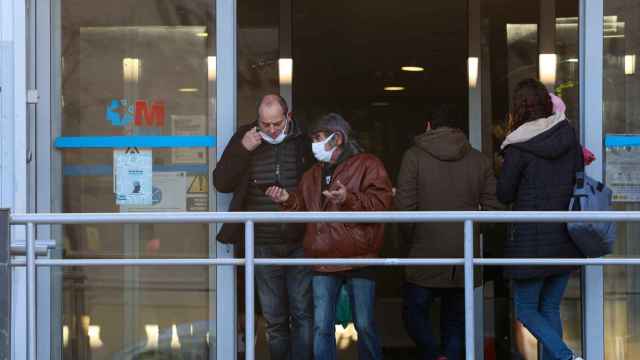 Dos personas con una mascarilla en la cara conversan a su salida de un centro de salud.