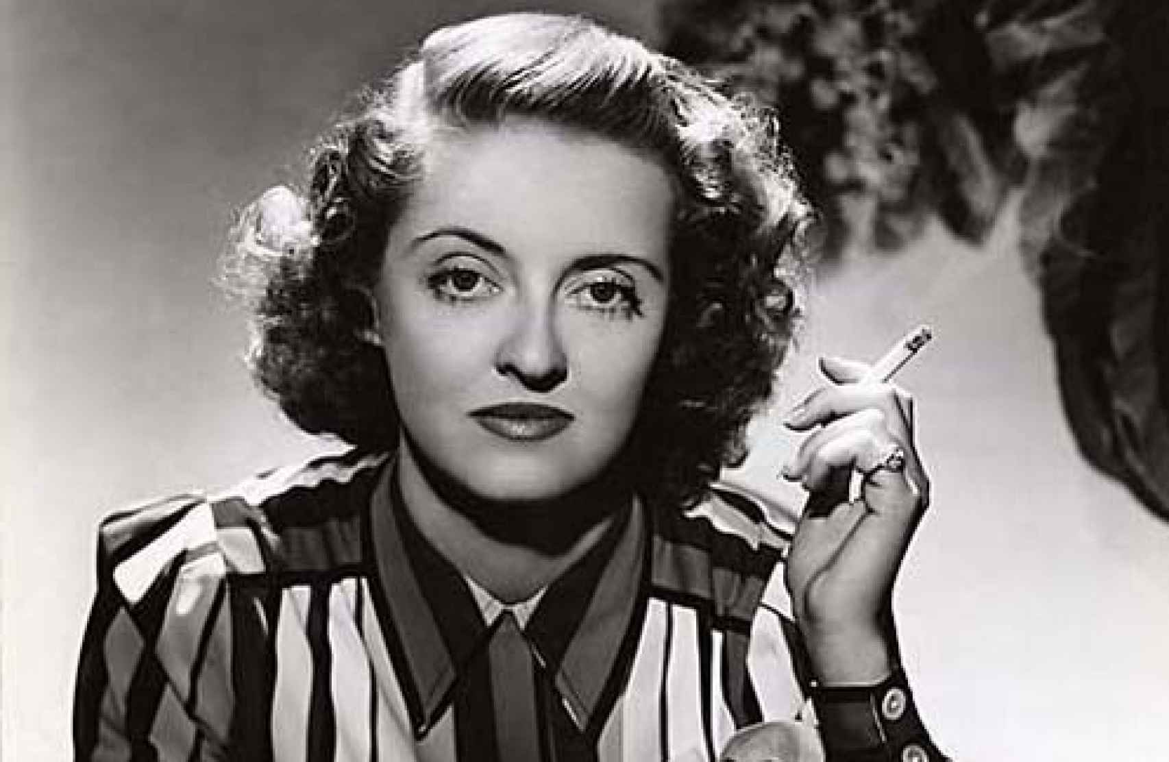 Bette Davis fumando un cigarro.