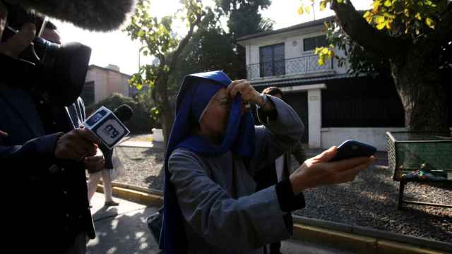La consagrada laica, Lorena Patricia Rámirez, tapándose la cara mientras periodistas intentan entrevistarla.