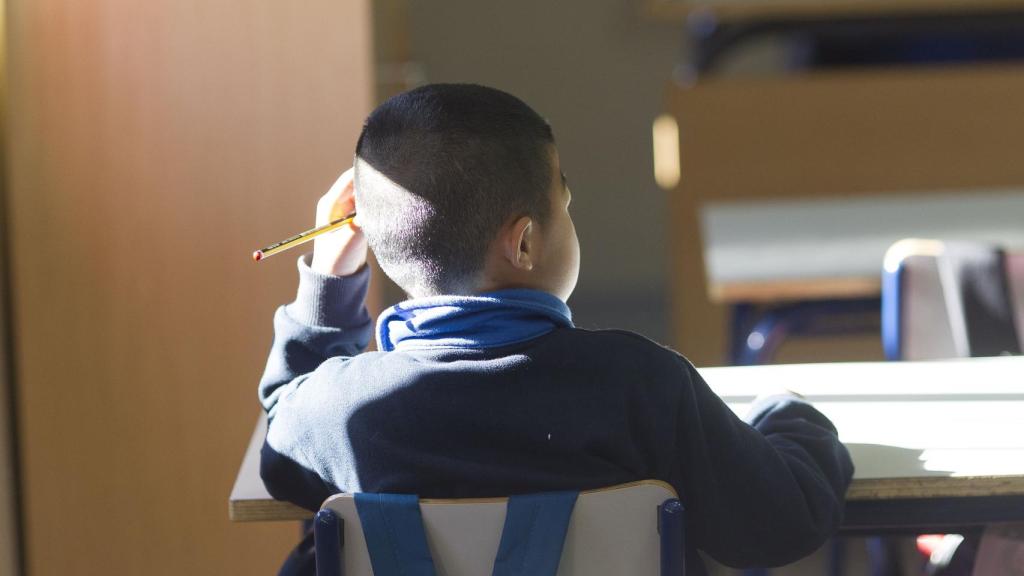 Un niño atiende al profesor en el colegio.