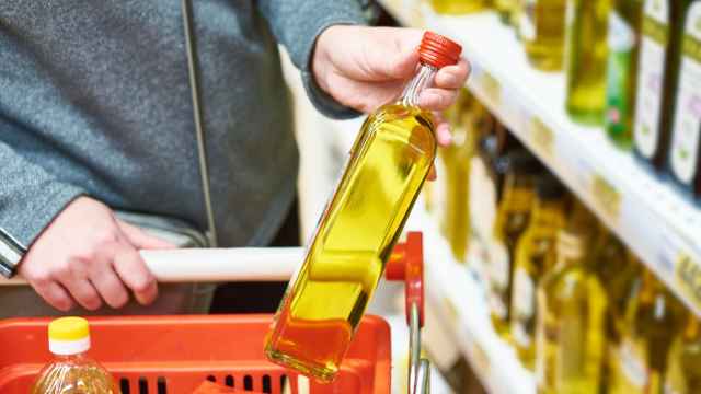 Una mujer cogiendo una botella de aceite en un supermercado.