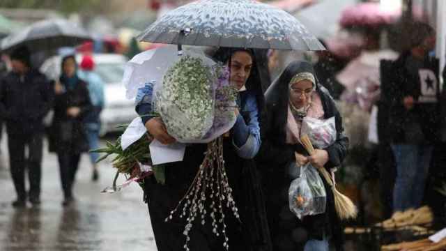 Mujeres iraníes caminan bajo la lluvia en un mercado de flores en Teherán.