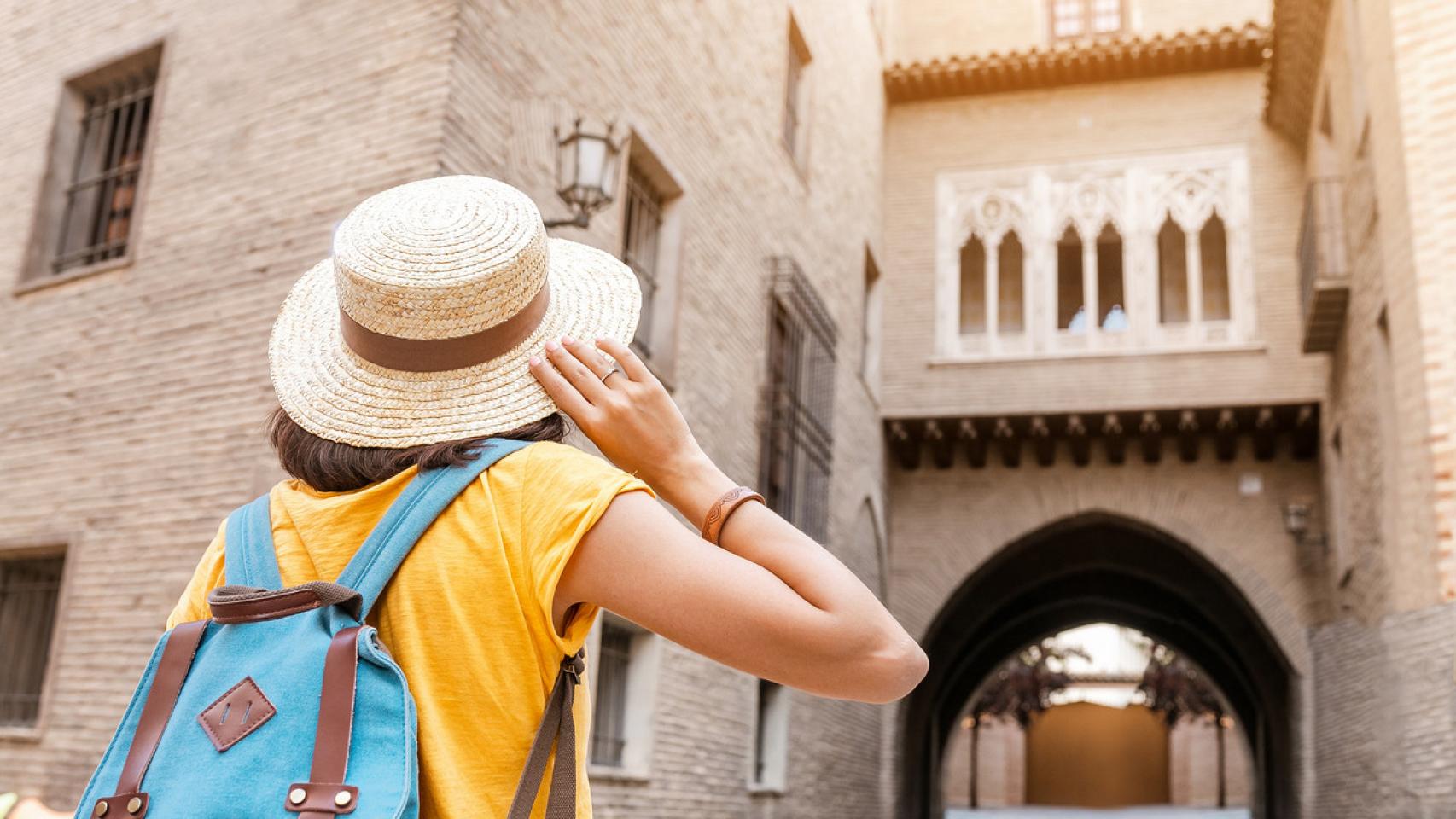 Una turista con sombrero mirando el balcón del casco antiguo de Zaragoza.