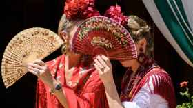 Dos mujeres vestidas de flamenca se protegen del sol en la Feria.