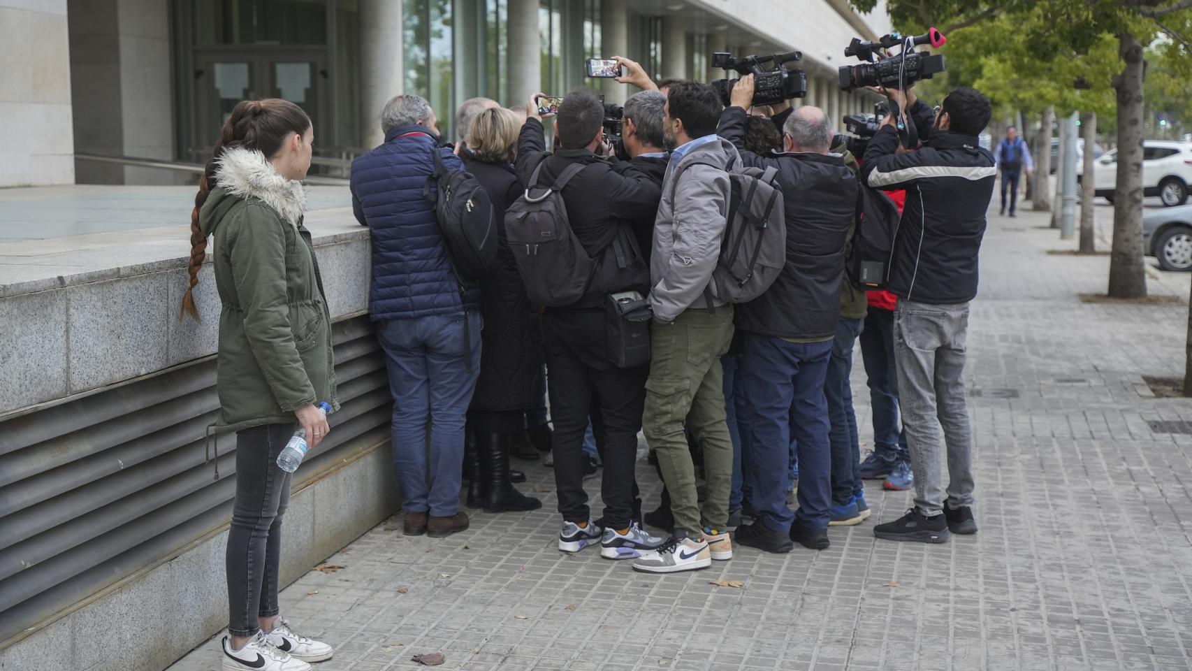 La joven que fue víctima de abusos del exmarido de Oltra mira a su abogado mientras atiende a los medios a las puertas de la Ciudad de la Justicia.