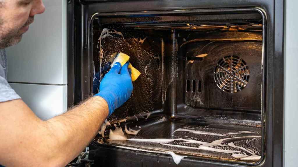 Imagen de archivo de una persona limpiando un horno.