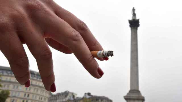 Una mujer sostiene su cigarrillo mientras fuma en Trafalgar Square en el centro de Londres el 1 de octubre.