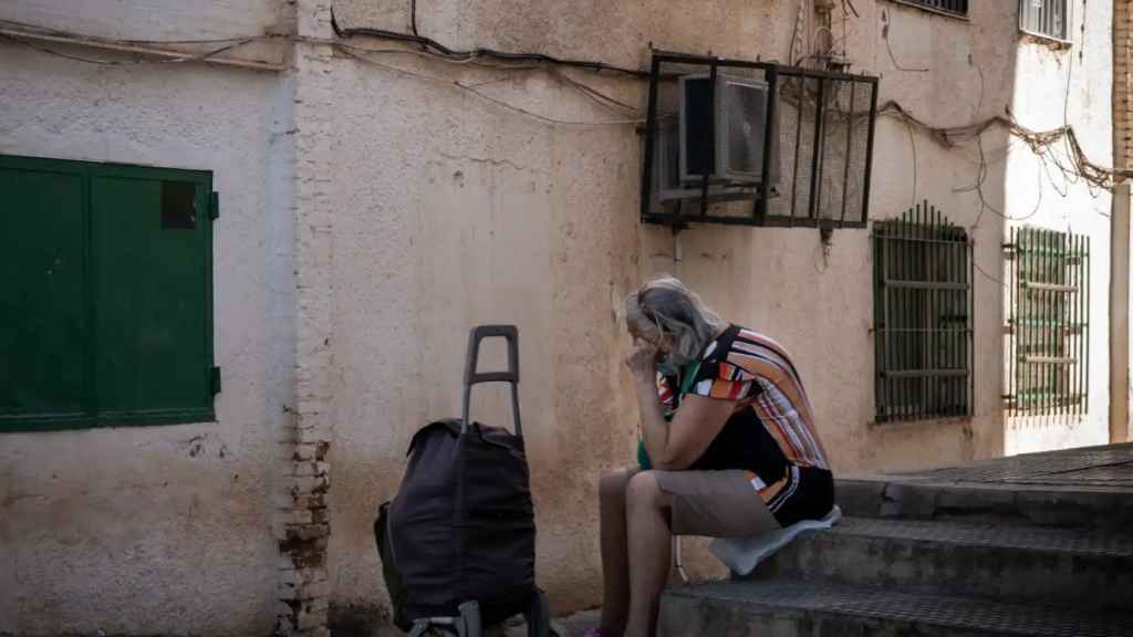 Una mujer descansa en el escalón de una calle en La Palmilla (Málaga).