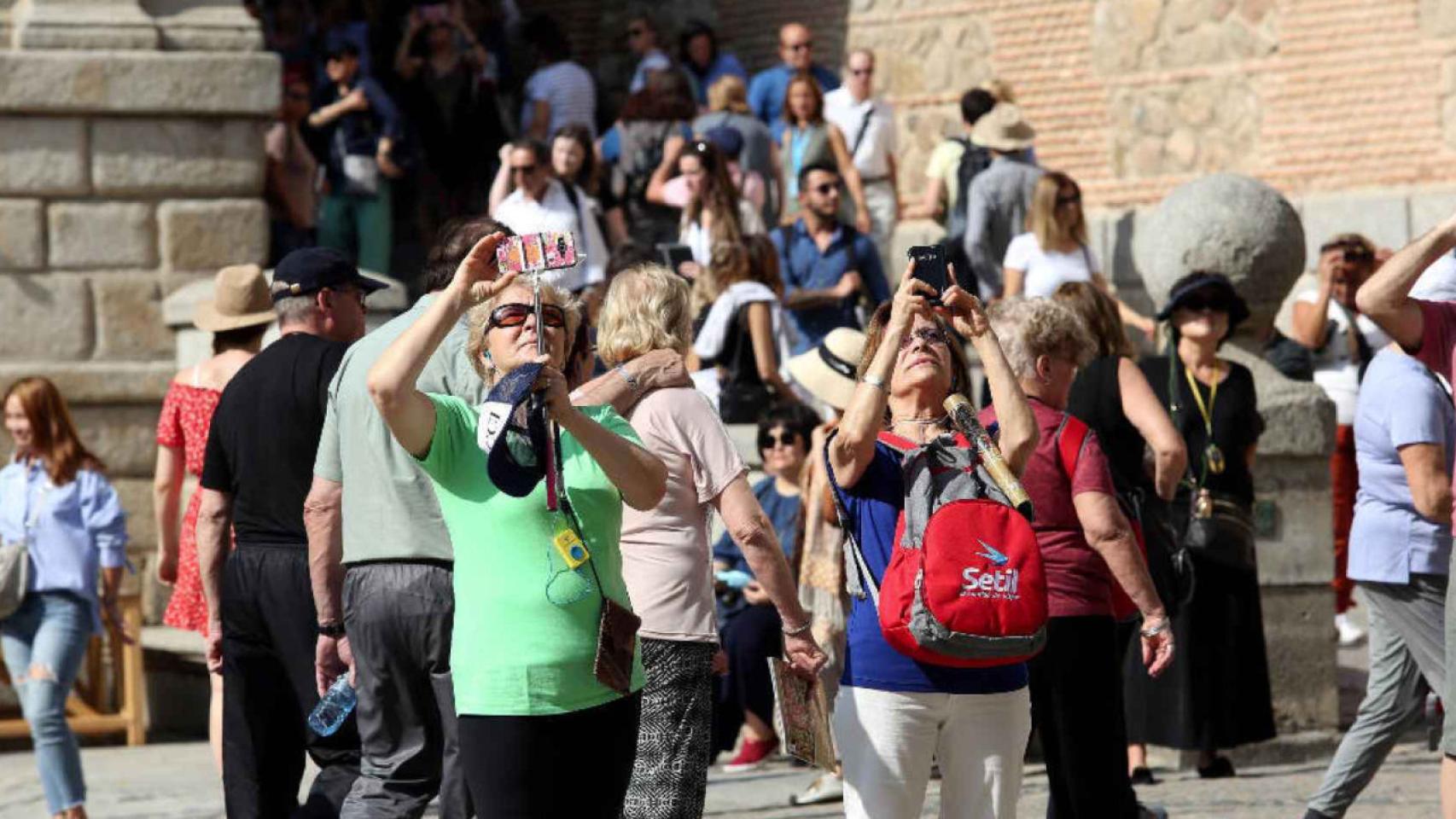 Varios turistas hacen fotos en la Plaza del Ayuntamiento de Toledo.