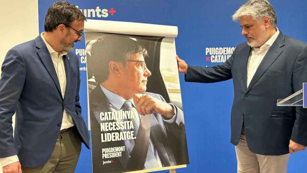 Josep Rius y Albert Batet, dirigentes de Junts, presentan el cartel electoral de Puigdemont para el 12-M, este miércoles.