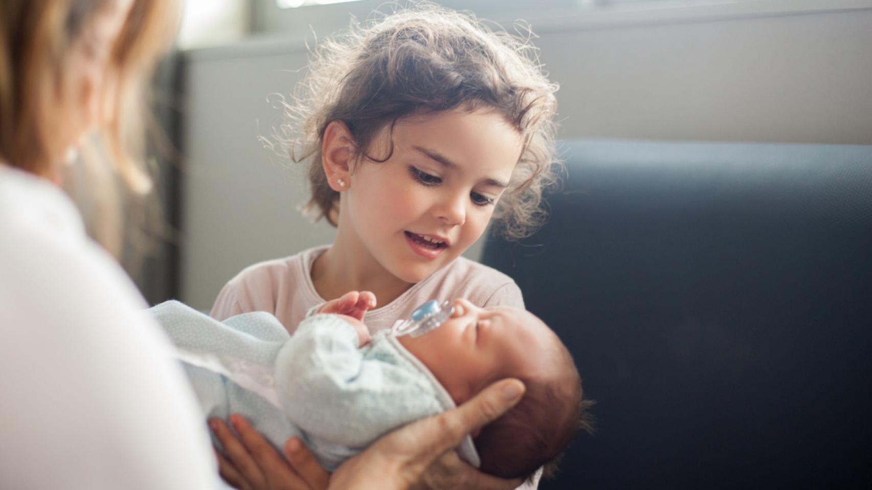 Niña cogiendo a un bebé.