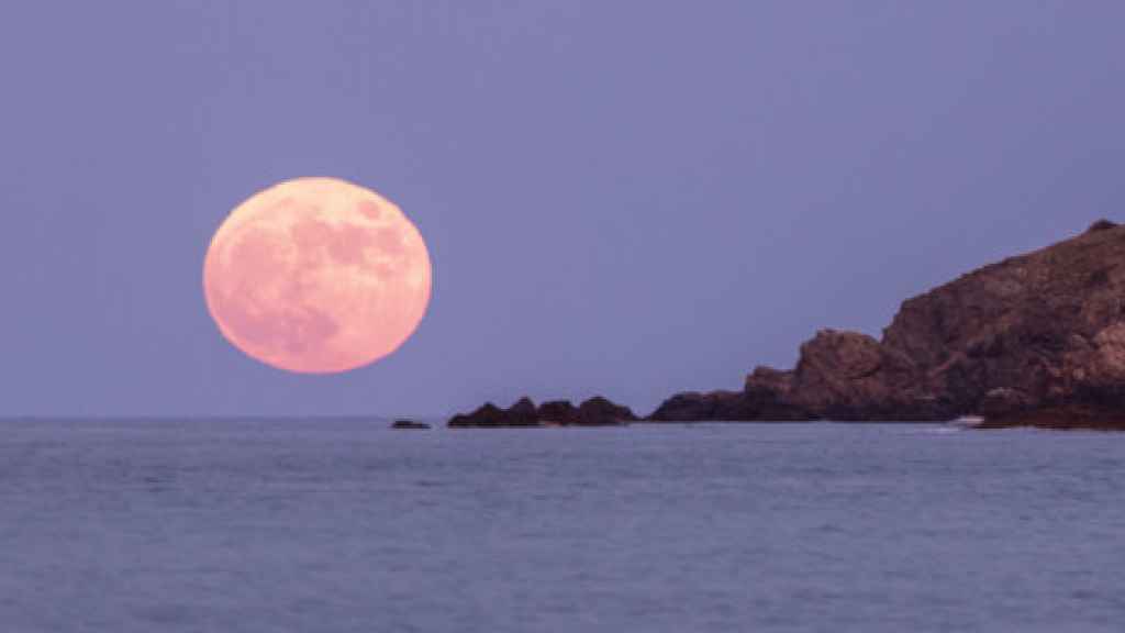 Luna rosa que se eleva sobre el mar Mediterráneo desde la playa de los amigos en la costa brava